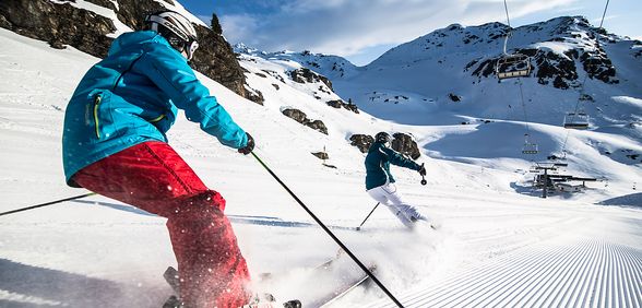 Skifahrer brettern in voller Fahrt die frisch präparierten Pisten hinunter